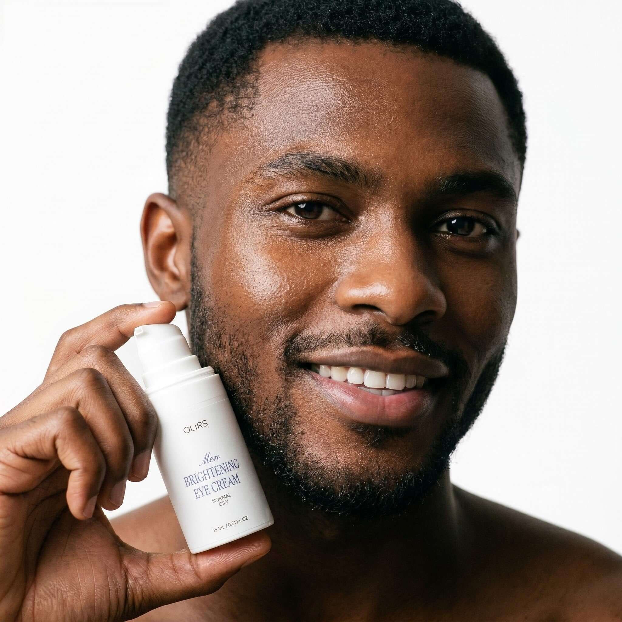 Man holding Brightening Eye Cream in a close-up photo, showcasing the product for tired-looking under-eyes.