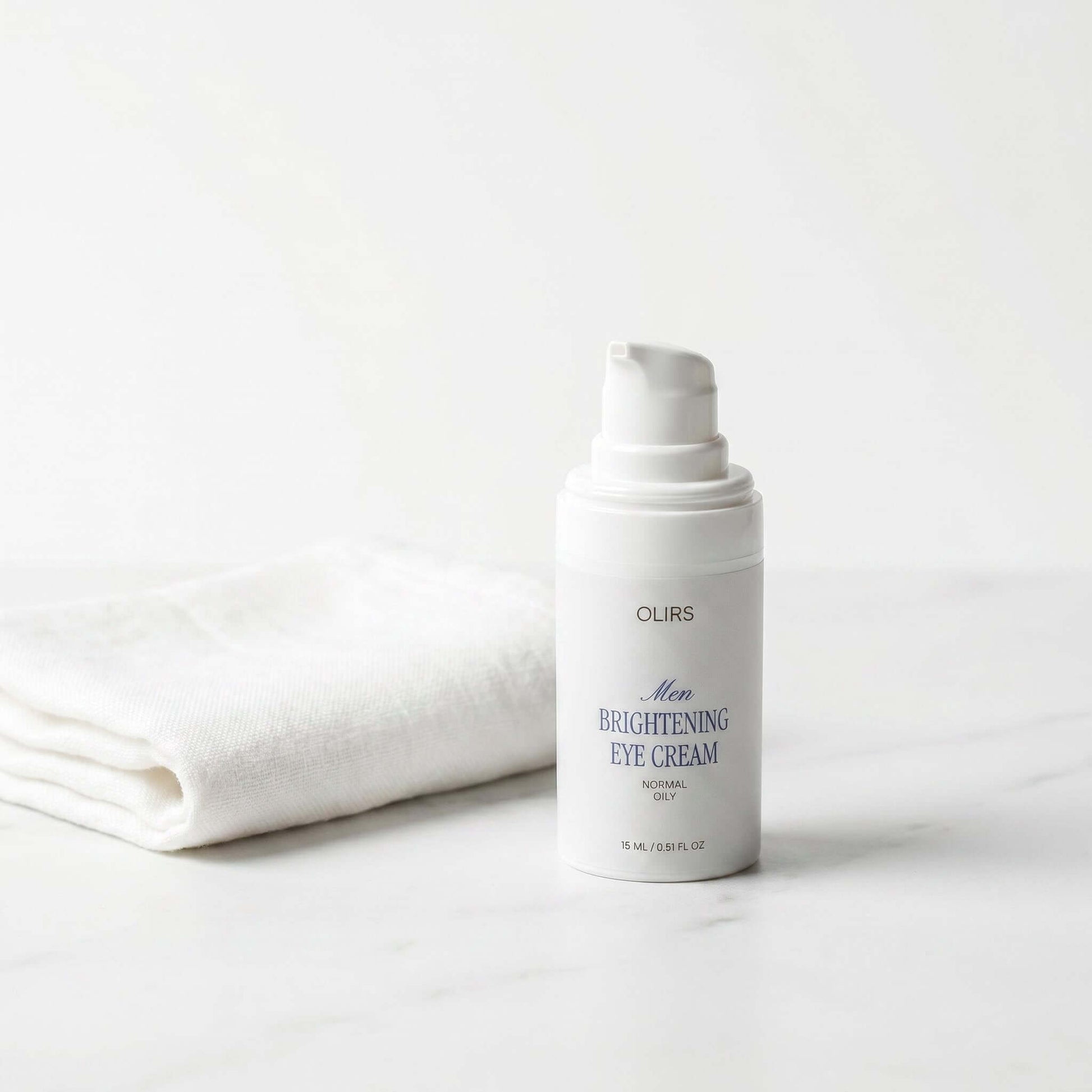 Men Brightening Eye Cream bottle on marble surface next to a white towel, ideal for reviving tired under-eyes.