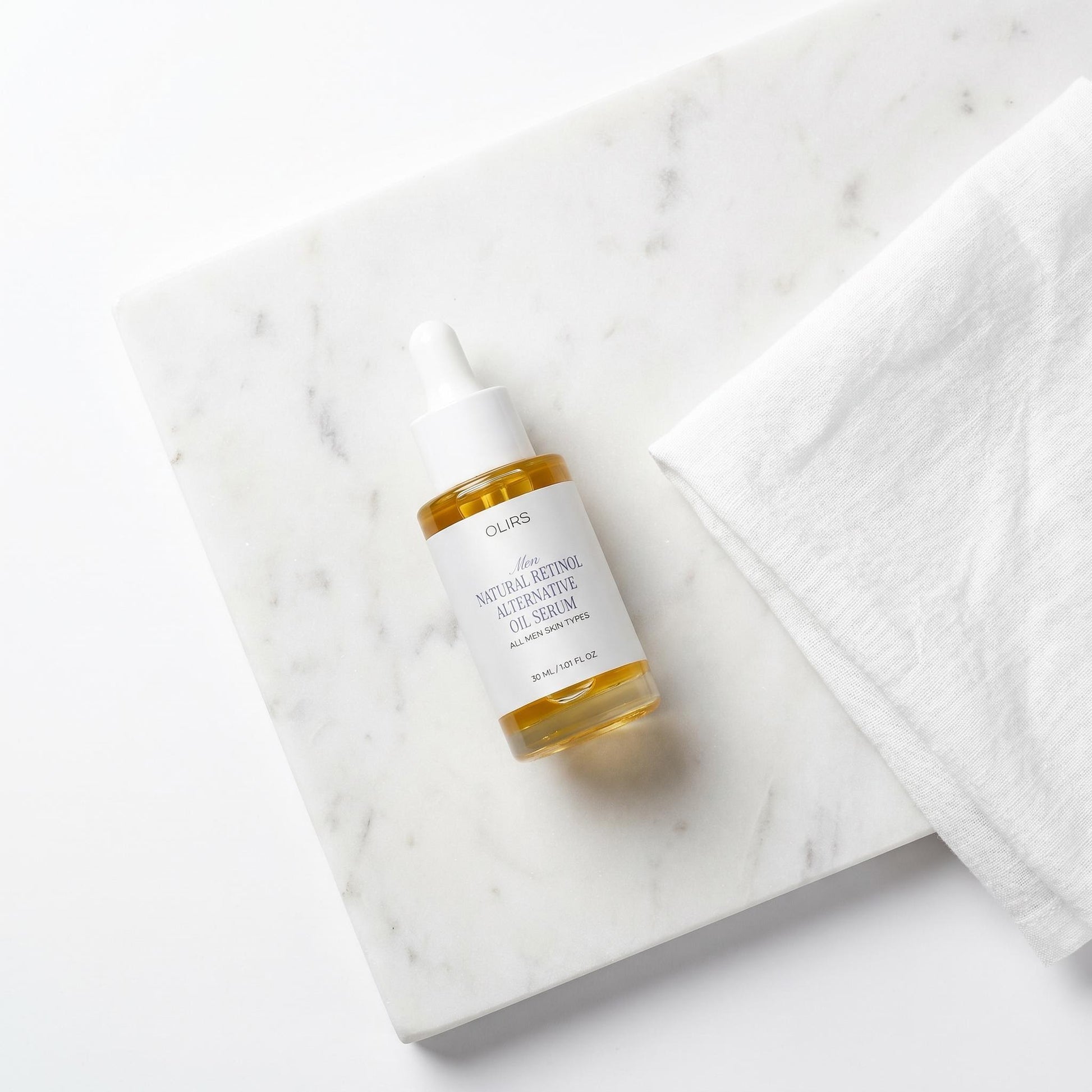 Bakuchiol Night Oil Serum on a marble surface with a white cloth.